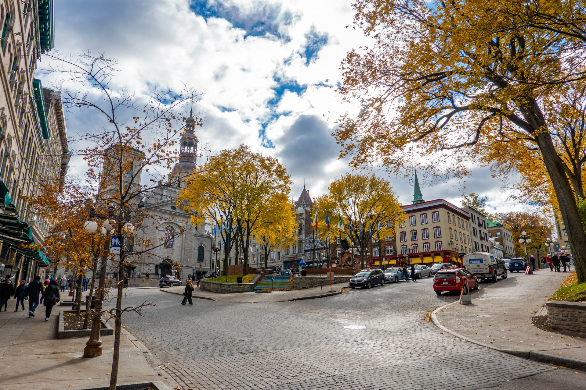 Autumn scene in Old Québec City with cobblestone street, colourful buildings, and golden trees.