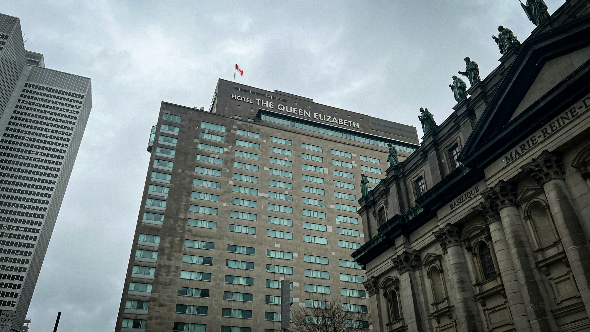 Hotel The Queen Elizabeth in Montreal beside Mary, Queen of the World Cathedral under a cloudy sky.